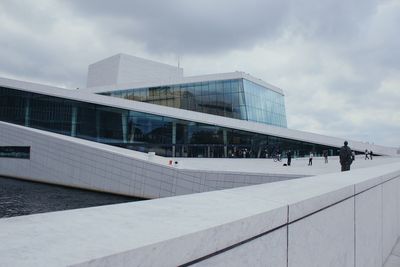 People in modern building against cloudy sky