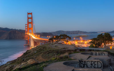 Illuminated bridge against sky at dusk