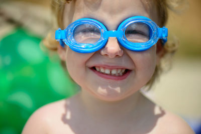 Close-up portrait of smiling girl wearing swimming goggles