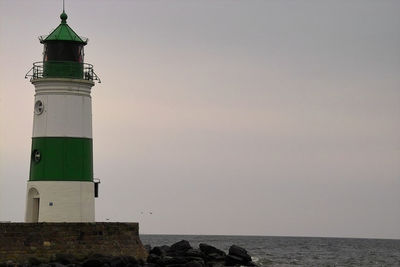 Lighthouse by sea against sky