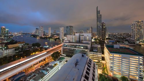 Illuminated cityscape against cloudy sky