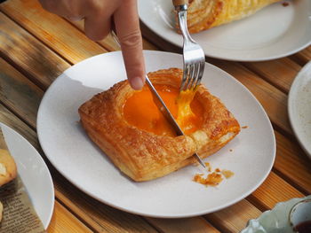 Cropped hand of woman having breakfast on table
