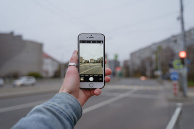 A man's hand with a ring holds a smartphone in his hand, leads a video filming of a pedestrian 