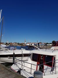 Sailboats moored in harbor against clear blue sky