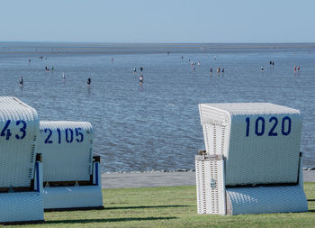 Hooded beach chairs on shore against sky