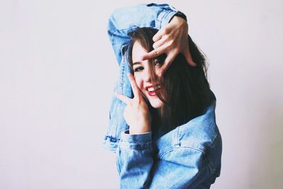 Portrait of young woman standing against white background