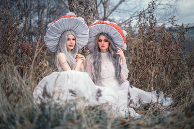 Portrait of woman wearing costume sitting with friend at field
