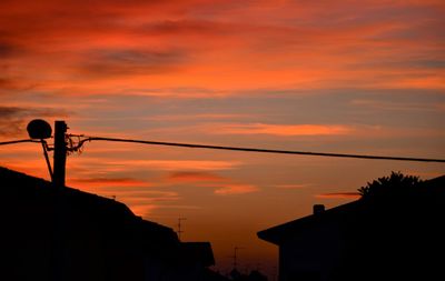 Low angle view of silhouette building against orange sky