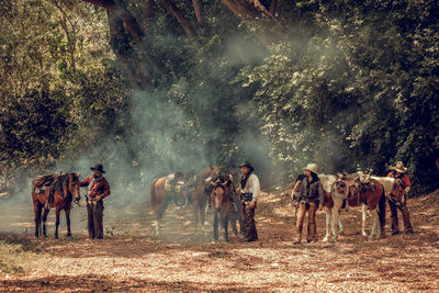 People with horses on land in forest