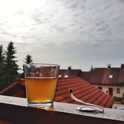 Close-up of beer glass on table against sky