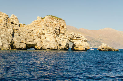 Scenic view of sea and rocks against clear blue sky