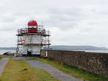 Lighthouse by sea against sky