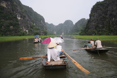 Rear view of people sitting on boat in lake