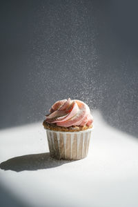 Cupcake on a dark background, which is sprinkled on top.