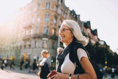 Smiling wrinkled woman looking away in city