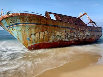 Abandoned boat at sea against sky