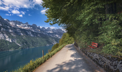 Road amidst trees and mountains against sky