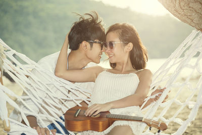 Young couple romancing by hammock at beach