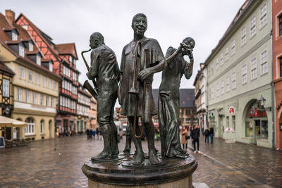 Statue in city against sky