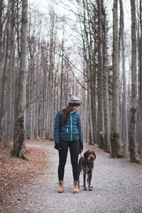 Full length of woman with dog in forest