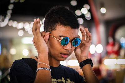 Young man wearing sunglasses against illuminated lights