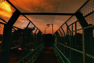 Illuminated railroad tracks against sky at sunset