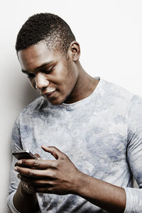 Young man using cell phone, studio shot