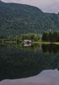 Scenic view of lake and sauna by trees against sky