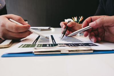 Midsection of man holding paper with toy on table