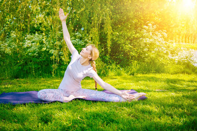 Rear view of woman doing yoga on field