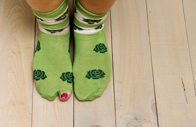 Low section of woman wearing green socks on wooden floor