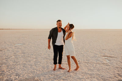 Full length of couple standing at beach
