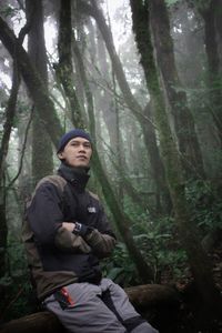 Full length of man standing amidst trees in forest