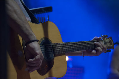 Cropped hand of man playing guitar during music concert