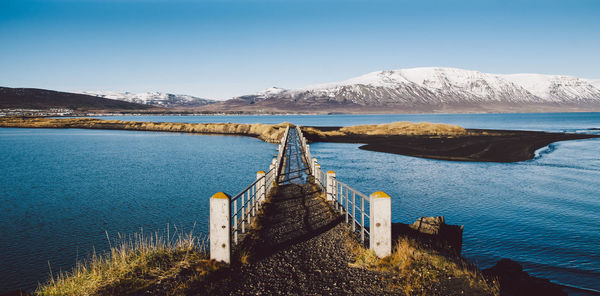 Scenic view of lake by mountains against clear blue sky