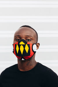 Closeup portrait of african american man wearing a colorful mask. he is looking at camera with serious expression