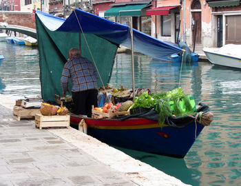 Rear view of vendor in boat at floating market on river