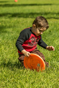 Boy playing with plastic disc on grassy field