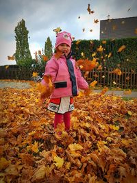 Full length of girl standing by autumn leaves