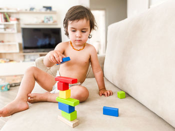 Toddler boy playing with wooden toy blocks at home