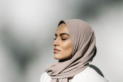 Young woman with eyes closed in front of white wall