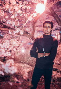 Portrait of young man standing by cherry tree