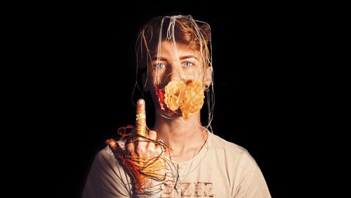 Portrait of woman gesturing by black background