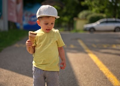 Portrait of little toddler in a park eating ice cream