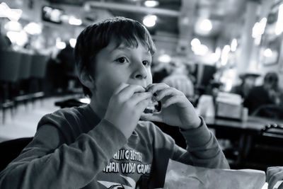 Cute boy eating food while sitting in restaurant