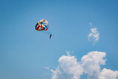 Low angle view of a kite flying in the sky, a man in a hot air parachute