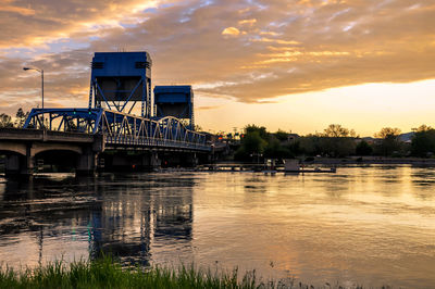 Bridge over river against sky at sunset