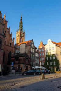 Cars on road by buildings against sky in city