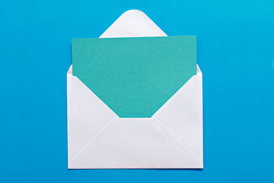 Close-up of envelope with blank paper against blue background