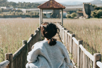 Rear view of woman standing by railing on field